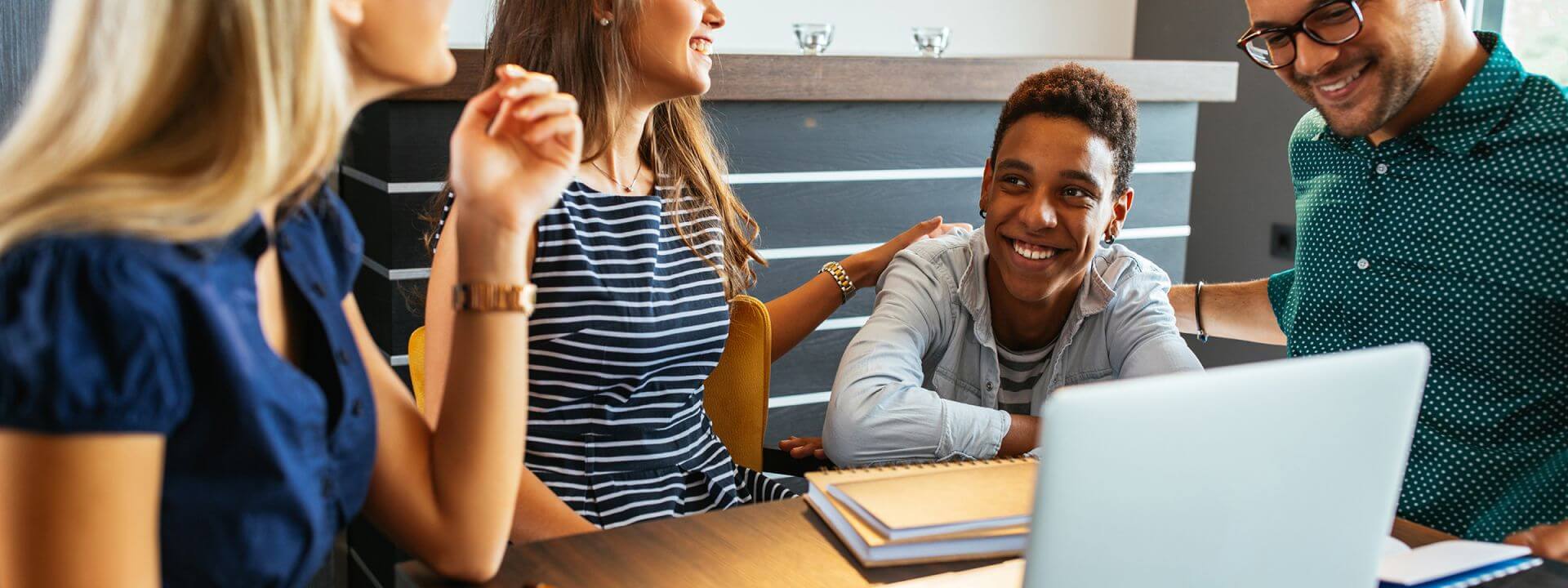 A group of people sitting around a table with a laptop.