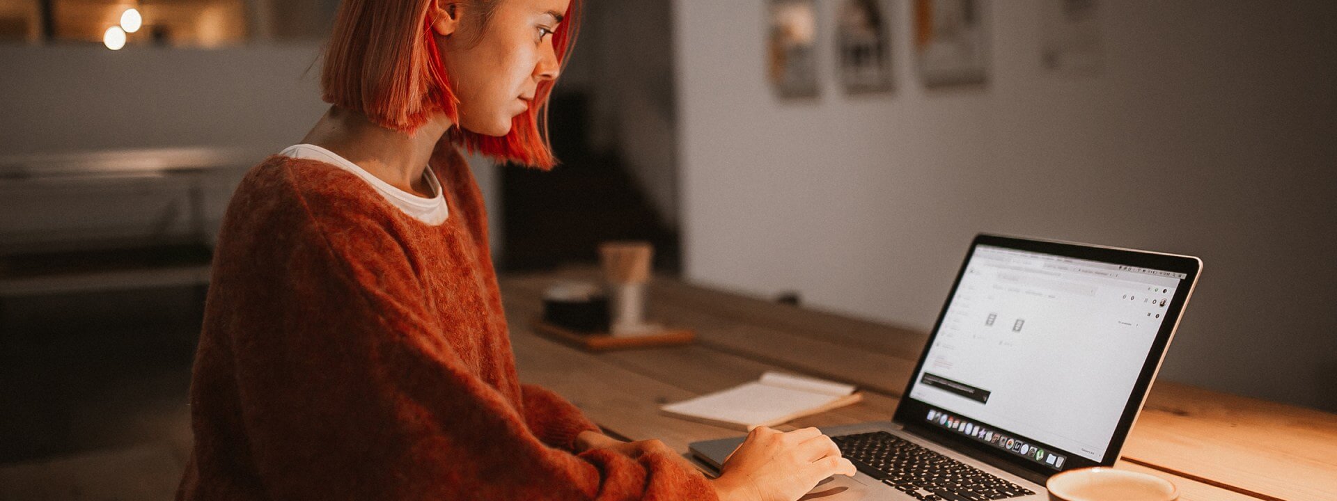 A woman working on a laptop in a dark room.
