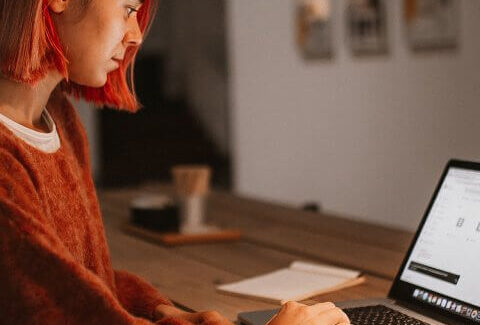 A woman working on a laptop in a dark room.