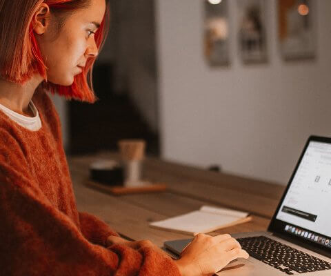 A woman working on a laptop in a dark room.