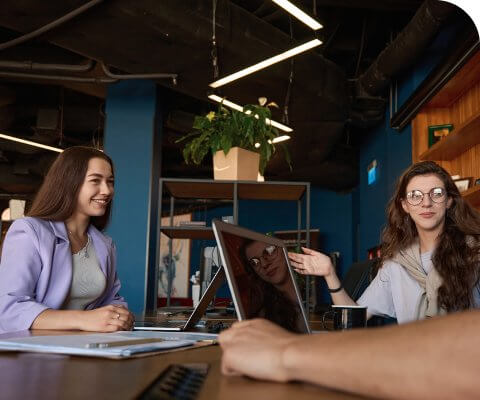 A group of people sitting at a table with laptops.