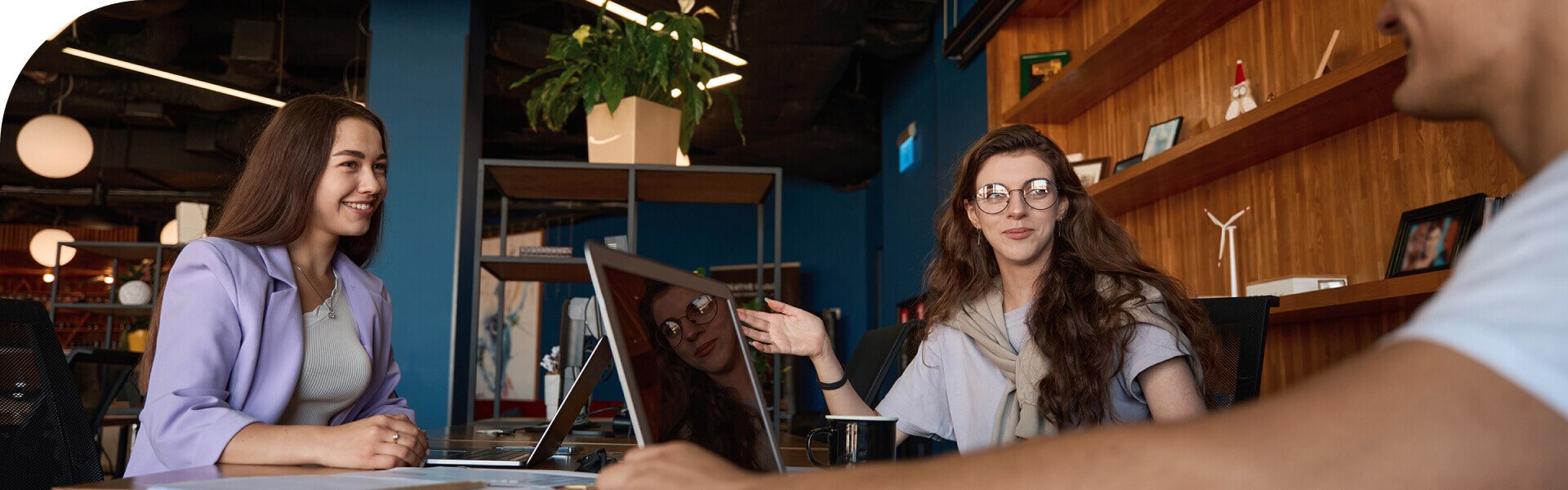 A group of people sitting at a table with laptops.