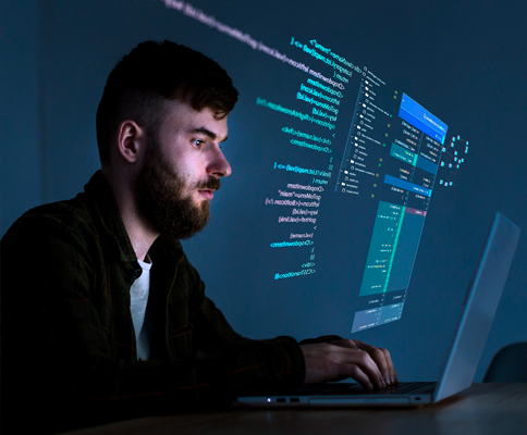 A man working on a laptop with code on the screen.