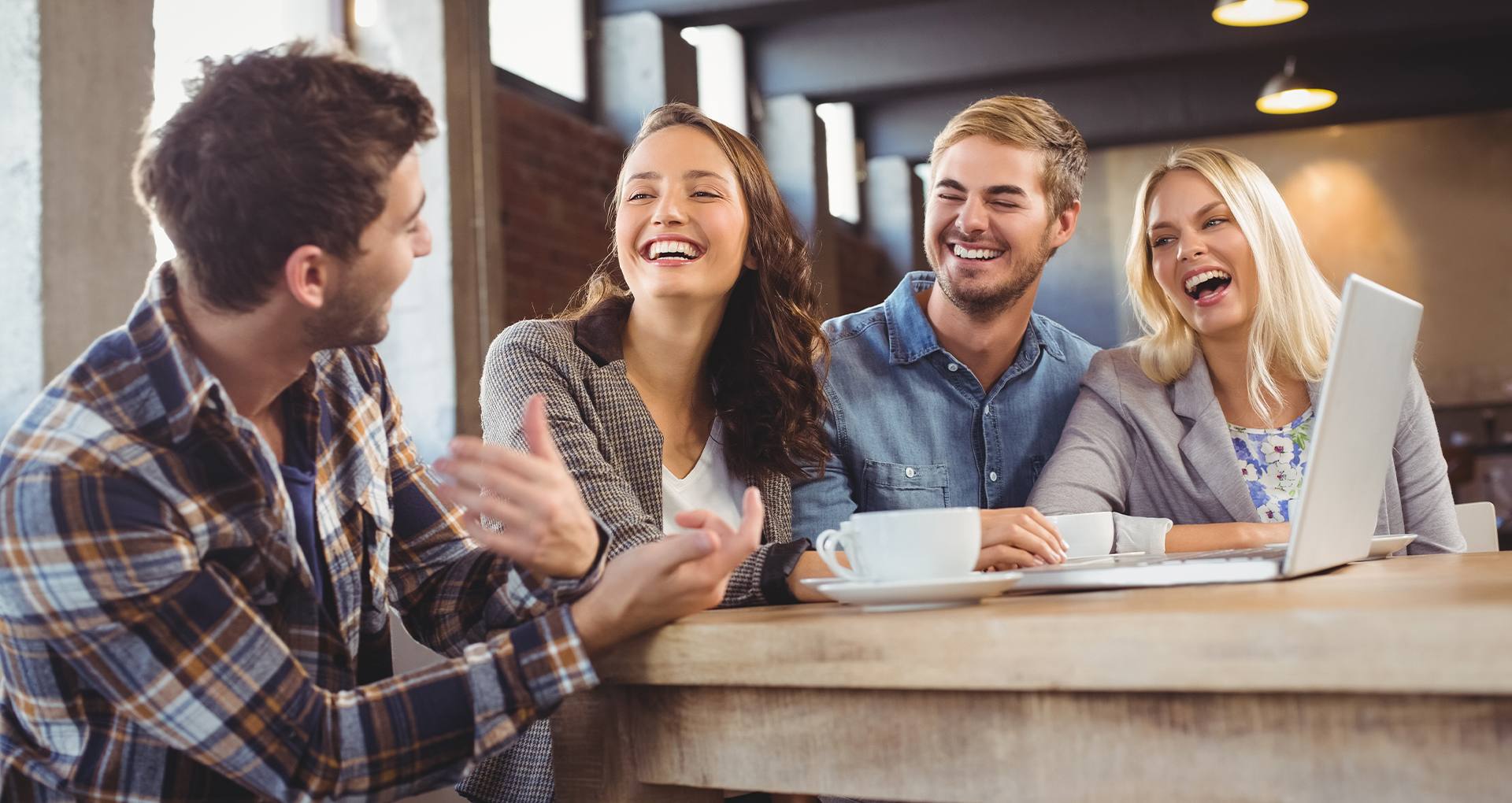 A group of friends laughing at a table in a coffee shop.
