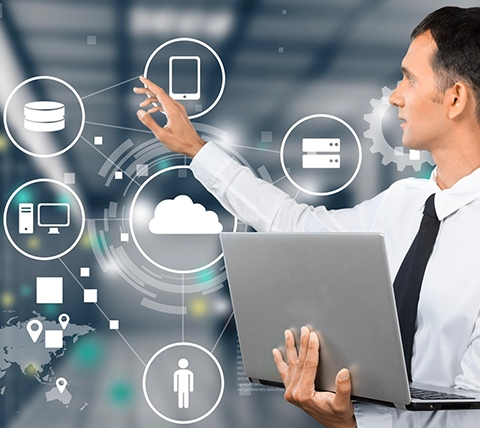 A man with a laptop in front of a server room.