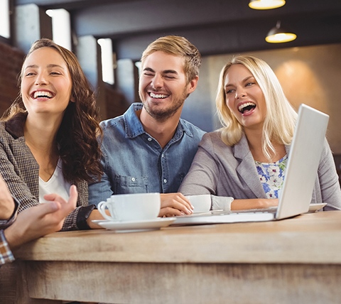 A group of friends laughing at a table in a coffee shop.